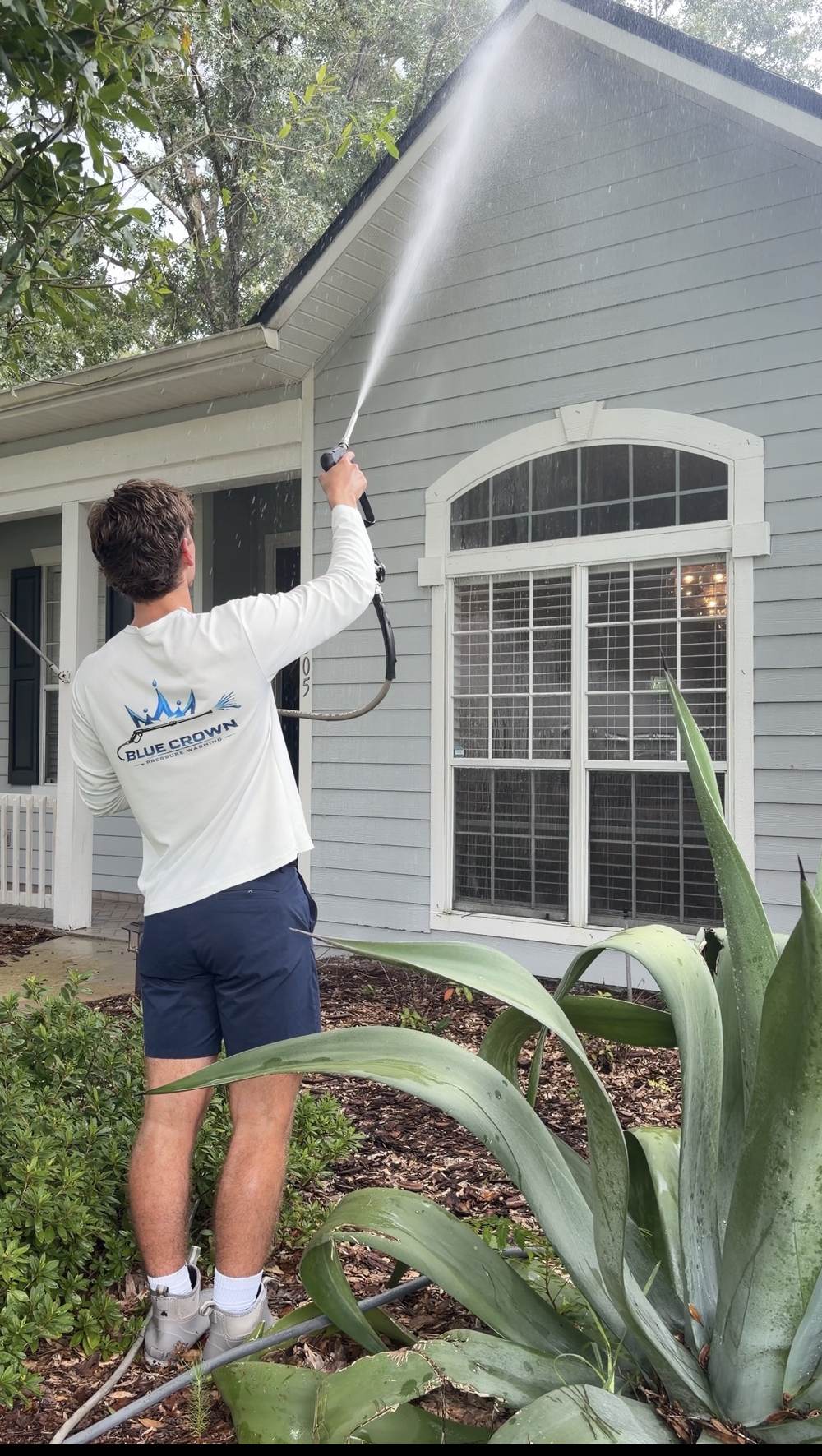Evan Ferrell, owner of Blue Crown Pressure Washing, house washing a home in Gainesville FL
